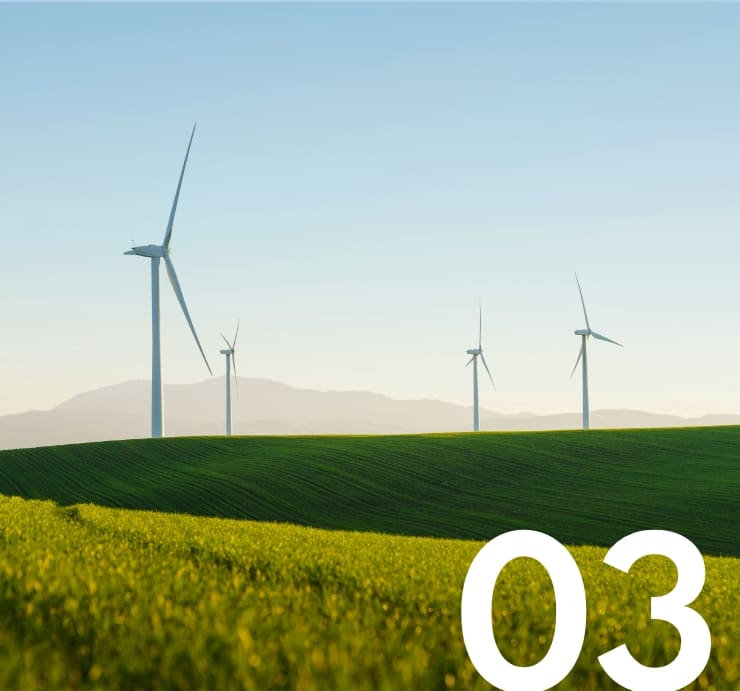 Row of wind turbines in green grassy hills with mountain in the distance.