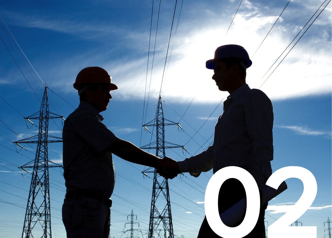 Two engineers in hard hats shaking hands with High-voltage power transmission lines and towers.